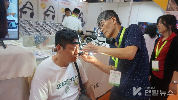 닥터킴 기기천 대표가 중국치과의사에게 헤드라이트루페를 착용시키고 있다. 